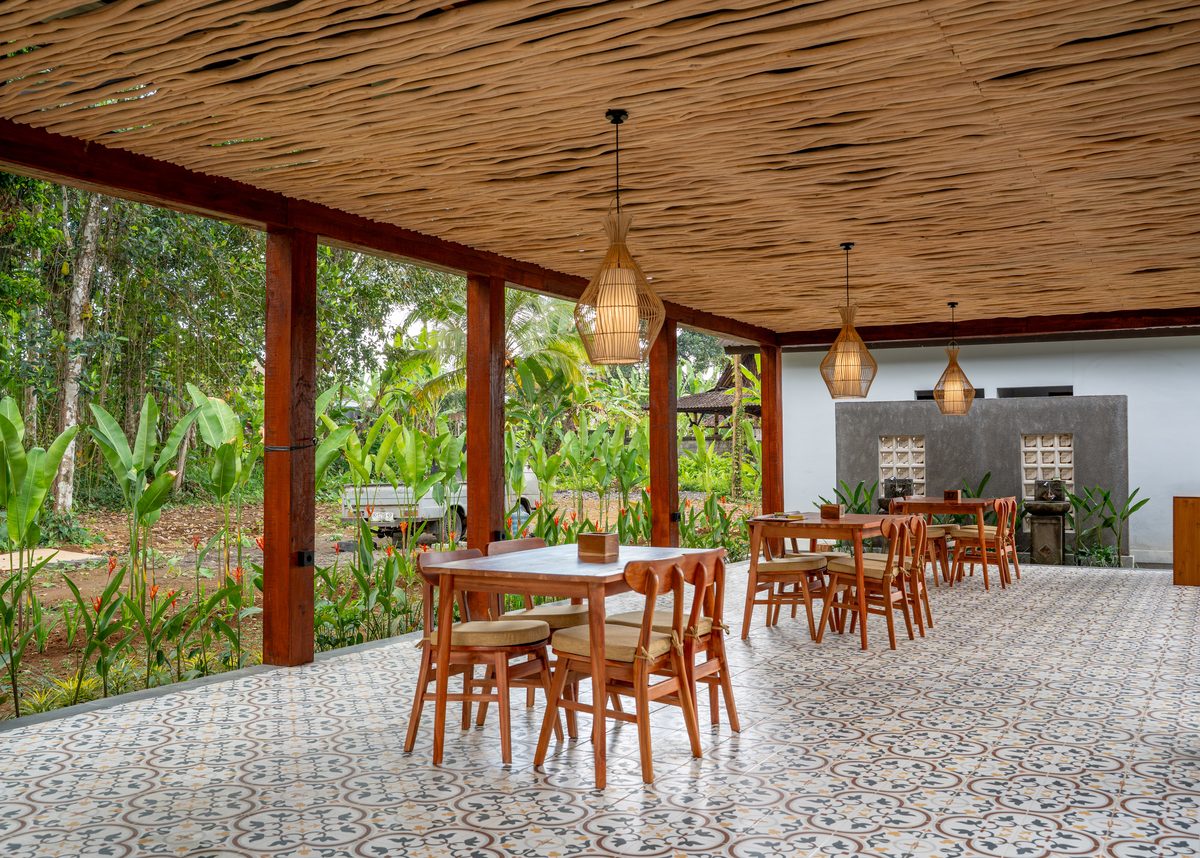 The open dining room under its woven bamboo ceiling, patterned tiles underfoot and the garden on three sides