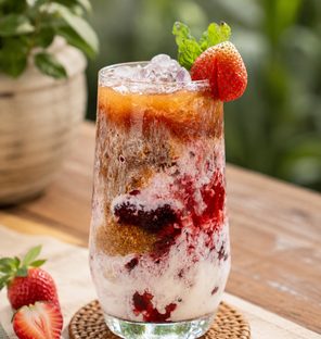 A berries soy latte, layered over ice and garnished with mint and strawberry